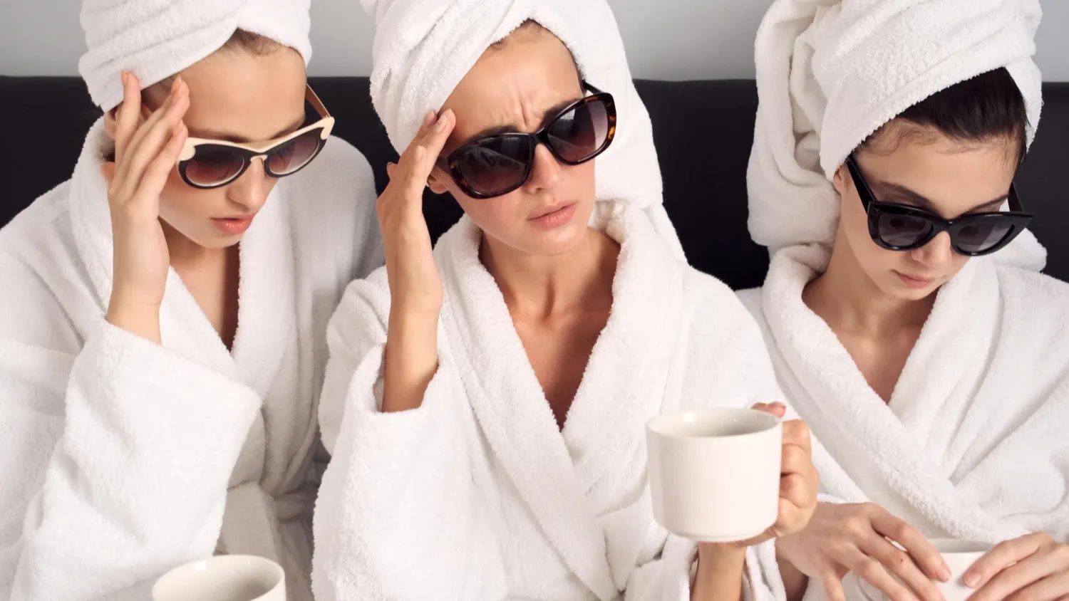 upset-girls-white-bathrobes-sunglasses-with-cups-coffee-having-headache-after-party-hotel-room-sad-expression (2)