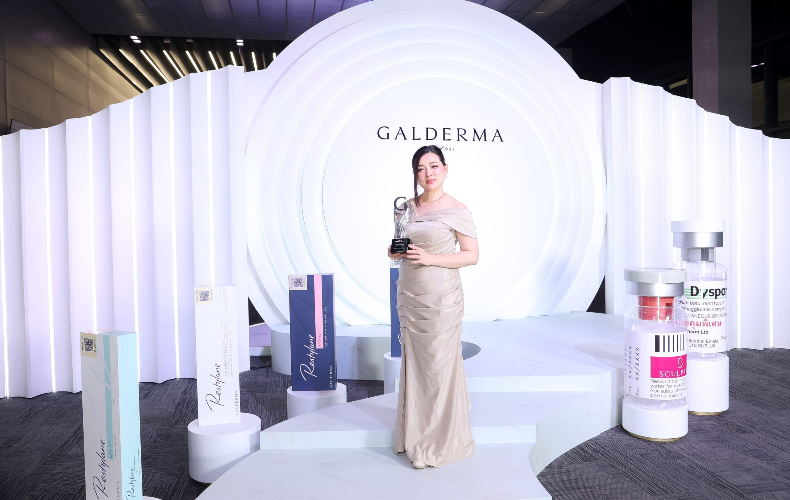 Woman holding award on Galderma stage with Restylane and Sculptra displays.