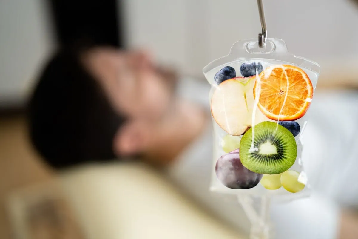 A person receiving a vitamin IV drip with fresh fruit in the bag.