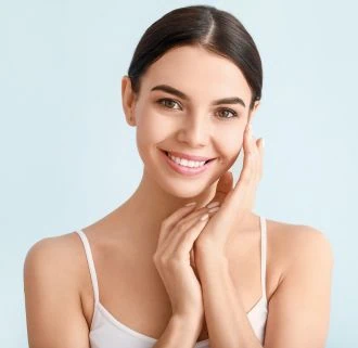Smiling woman with clear radiant skin touching her face gently.