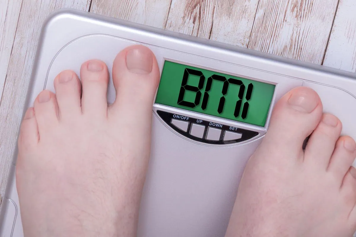 Bare feet standing on a digital scale displaying BMI.