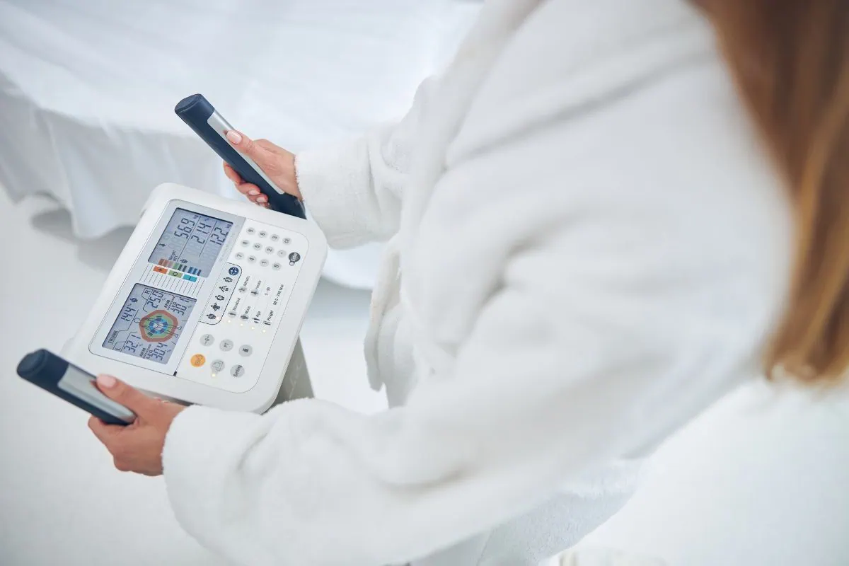 Woman in white robe using body composition analyzer machine.