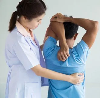 Physical therapist assisting male patient with shoulder stretching exercise.
