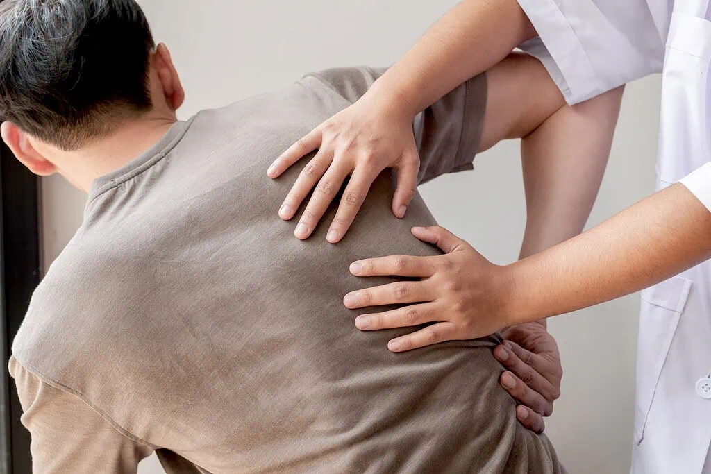 Medical professional in white coat treating patient's back