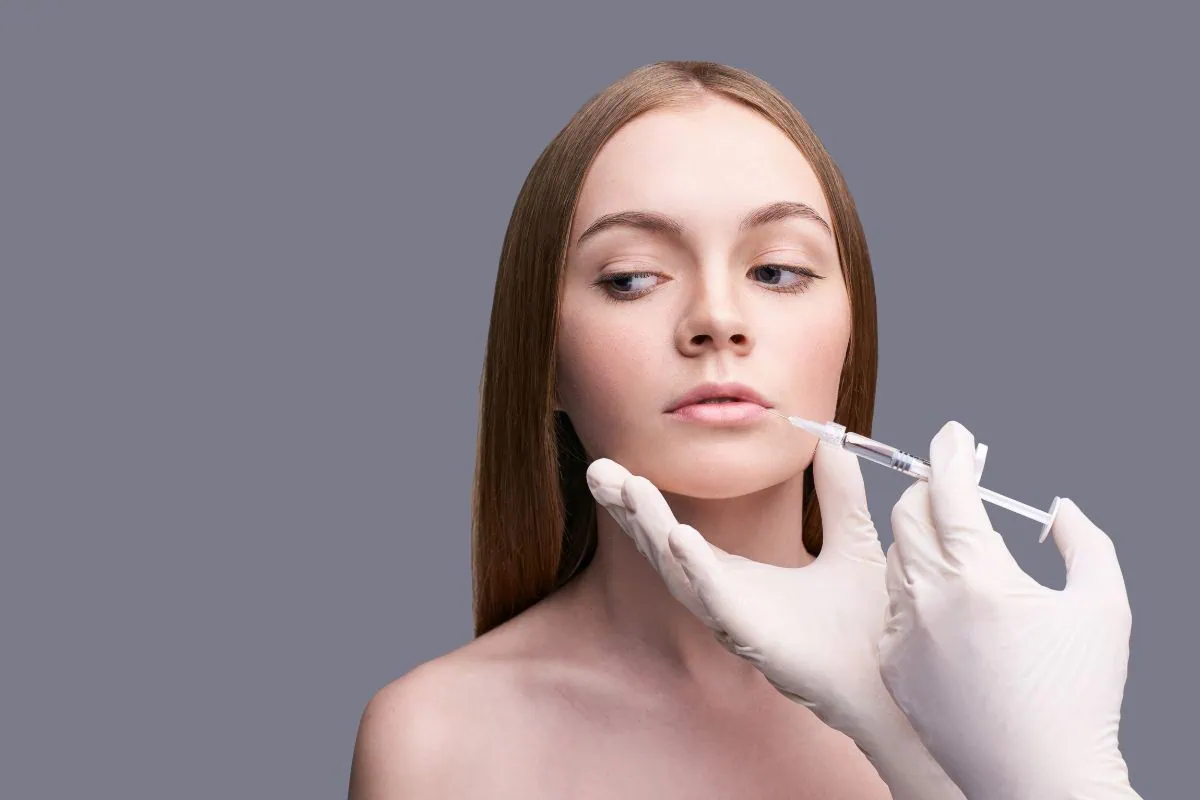 Woman receiving cosmetic dermal filler injection near lips.