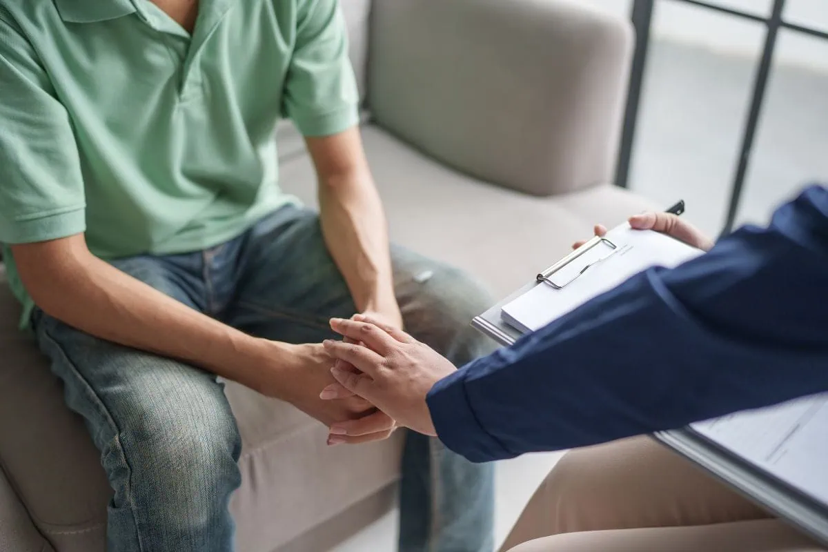 Medical professional holding patient hands during consultation.