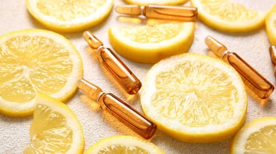 Brown glass skincare ampoules mixed with fresh lemon slices.