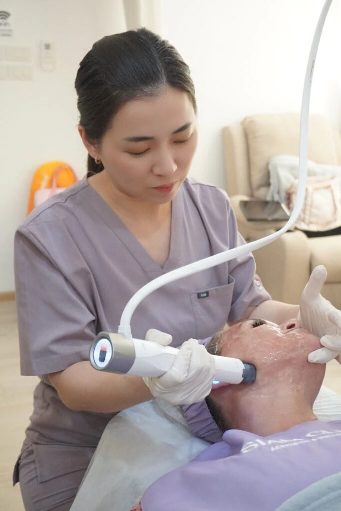 Aesthetician using handheld device for facial skin treatment on patient.