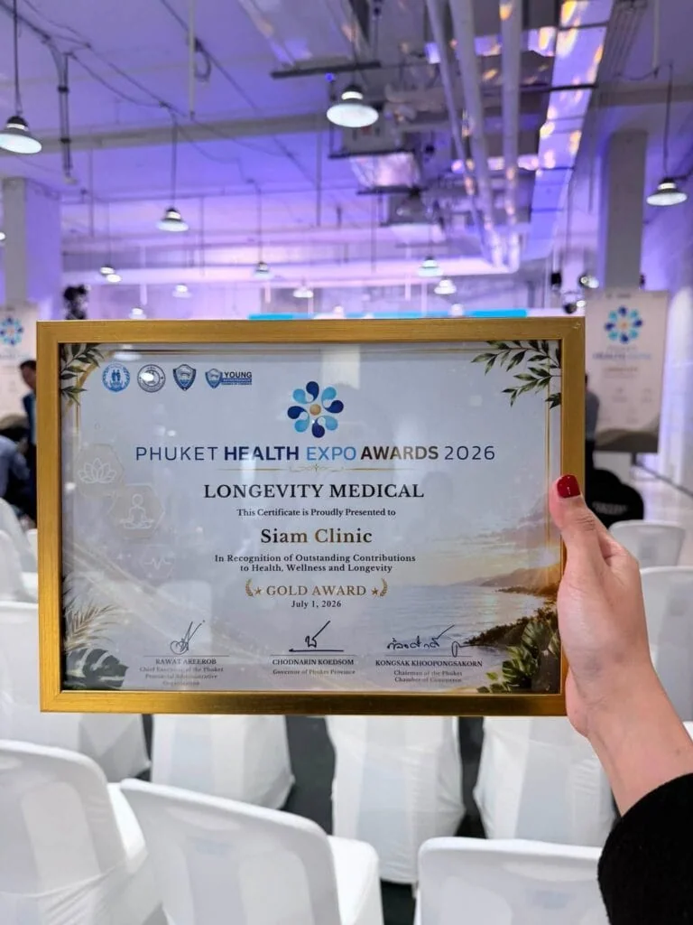Person holding a framed award certificate at Phuket Health Expo 2026, recognizing Siam Clinic with the Gold Award for Longevity Medical.