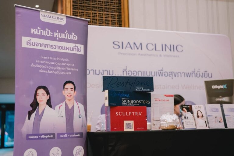 Siam Clinic booth at a conference with promotional banners and product displays, including skincare and wellness products, in a conference hall setting.