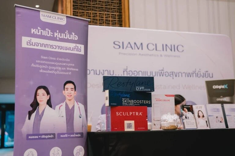 Siam Clinic booth at a conference with promotional banners and product displays, including skincare and wellness products, in a conference hall setting.