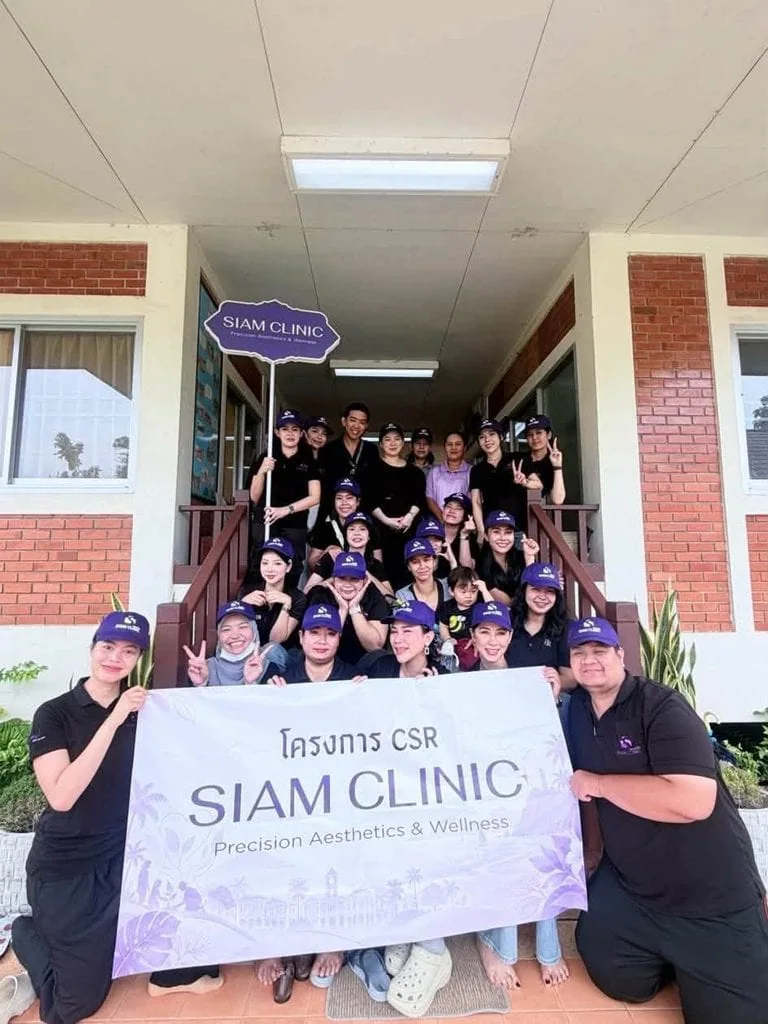 Group of people holding a banner in front of Siam Clinic building during a CSR event at Baan Sosa Phuket.