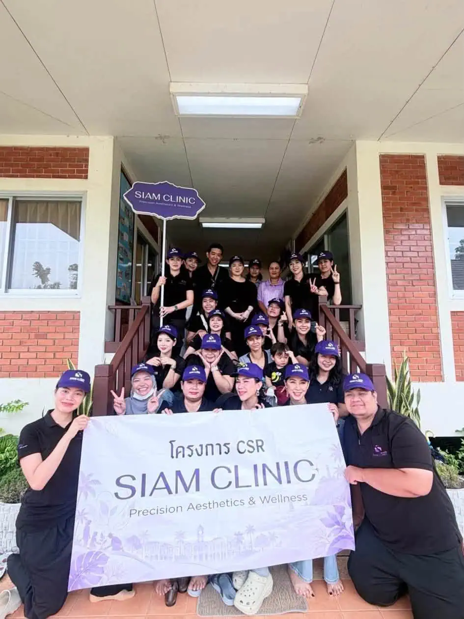 Group of people holding a banner in front of Siam Clinic building during a CSR event at Baan Sosa Phuket.